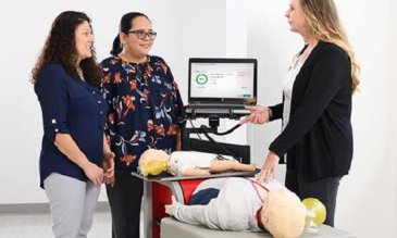 An instructor teaching two students CPR