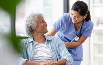 A female patient in a wheelchair smiling at a female nurse