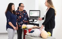 An instructor teaching two students CPR